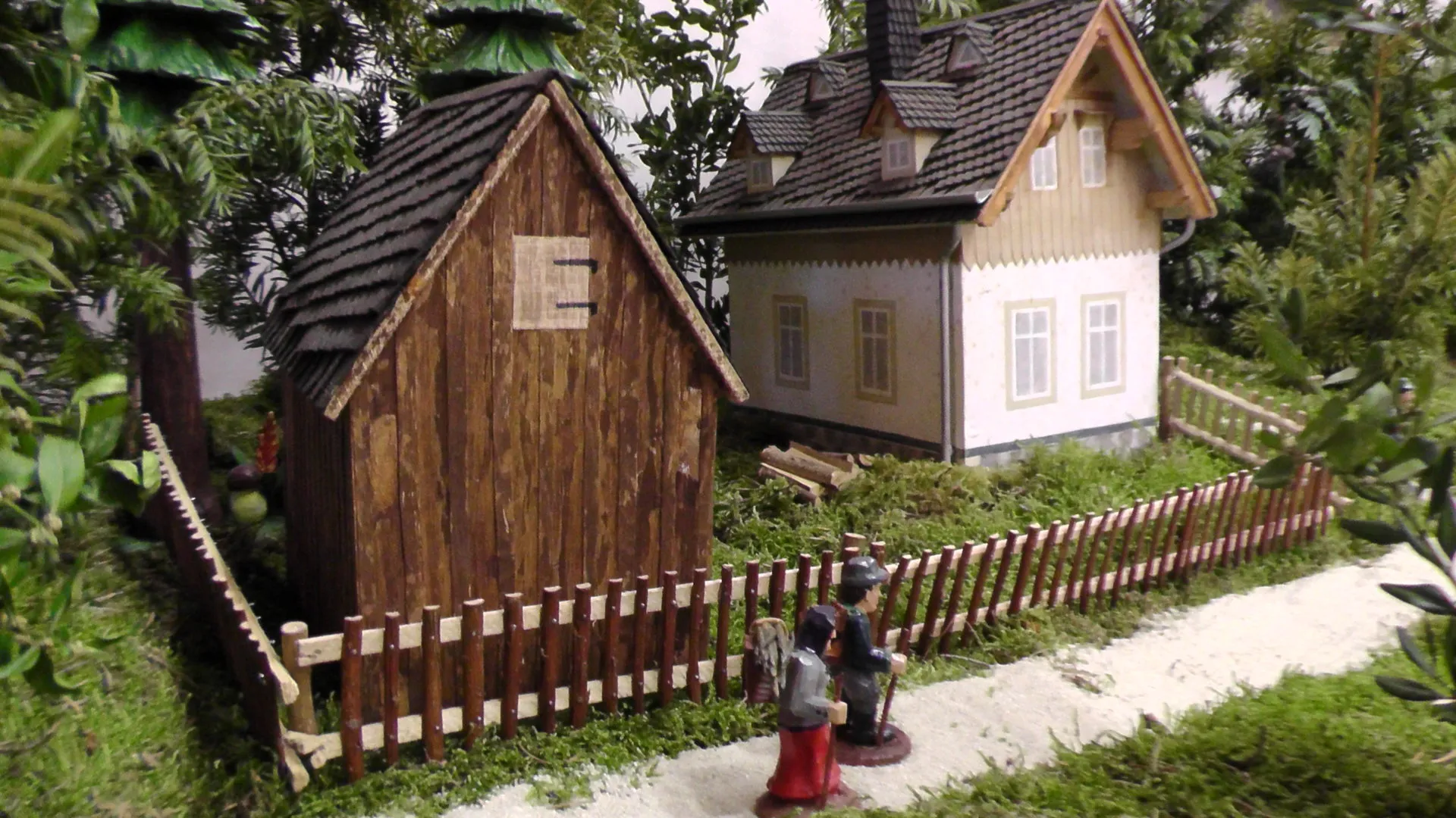 Modell des Bornwalddorfes: Holzschuppen und Wohnhaus hinter einem geschnitzten Lattenzaun