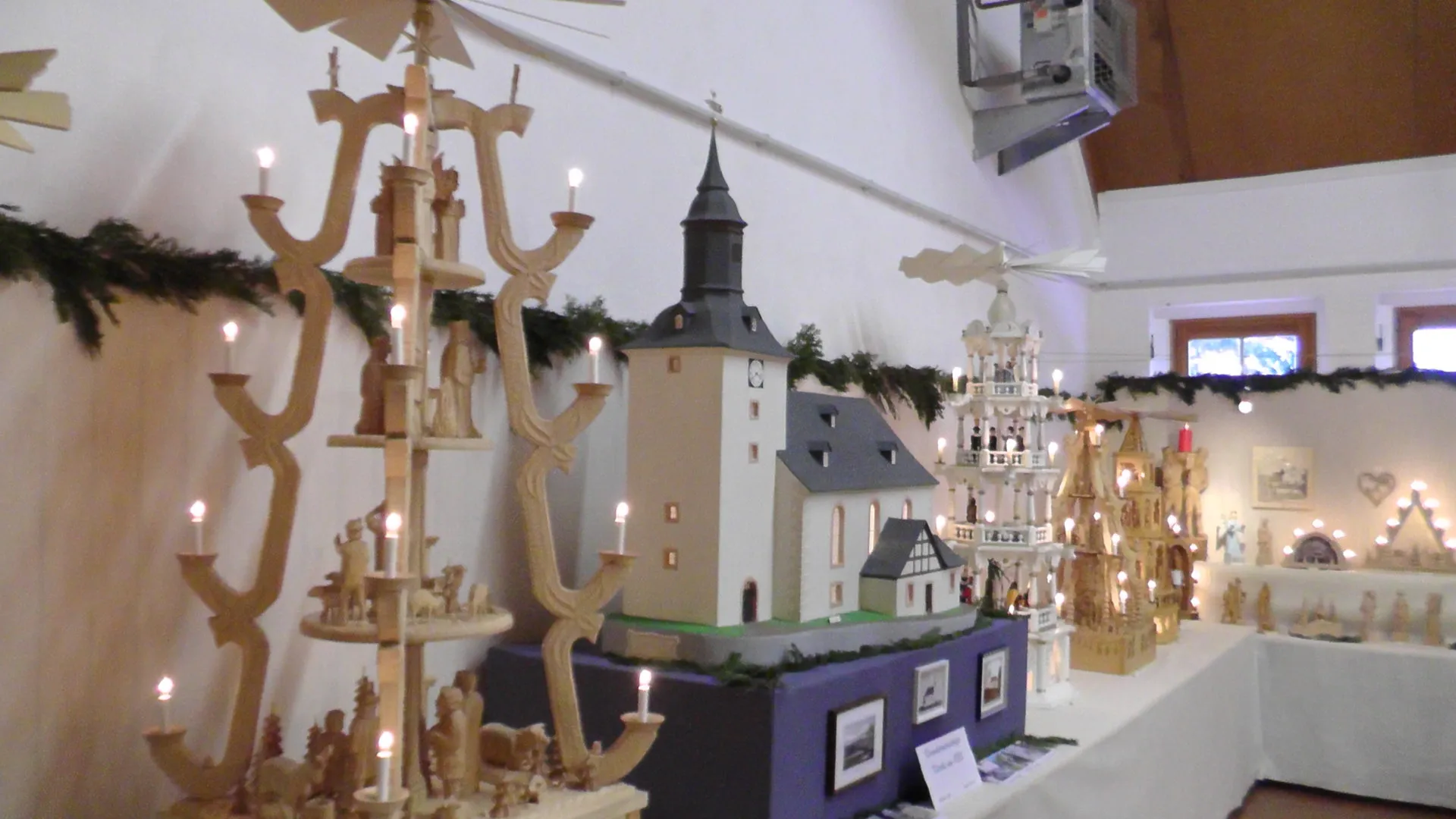 Ausstellungsraum mit Stufenpyramiden, einem Modell der Dorfkirche und beleuchteten Schwibbögen
