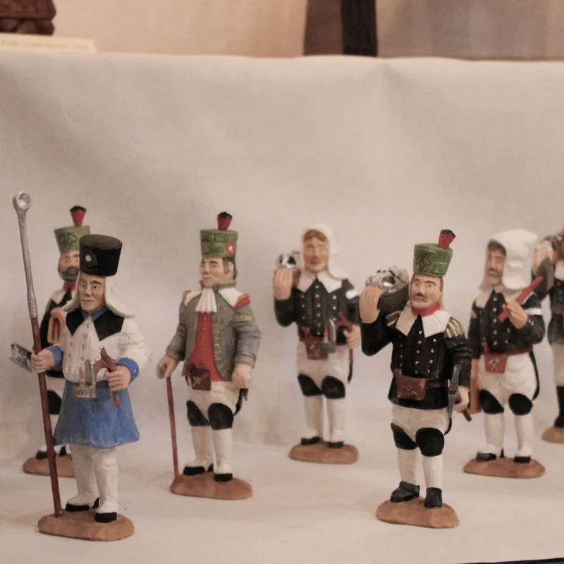 Bemalte geschnitzte Bergmannsfiguren einer Bergparade in schwarz-weißer Tracht mit grünen Schachthüten